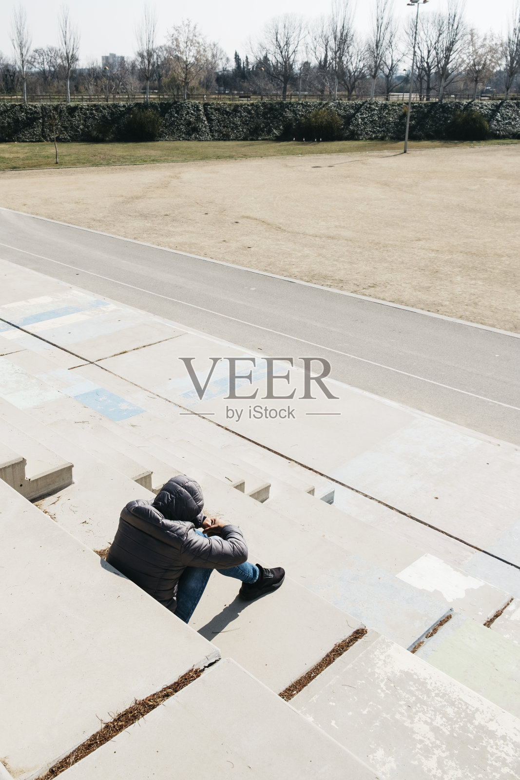 一名男子蜷缩着坐在室外的楼梯上照片摄影图片