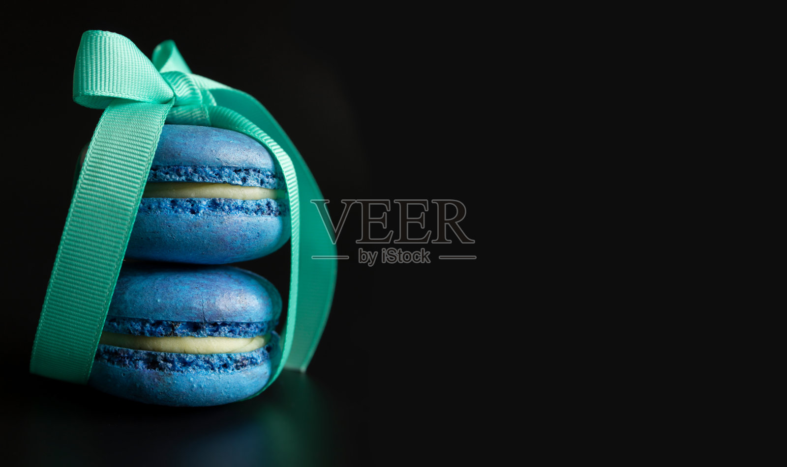 两个蓝色的马卡龙与绿松石缎带在一个深色的背景和文字/复制空间照片摄影图片