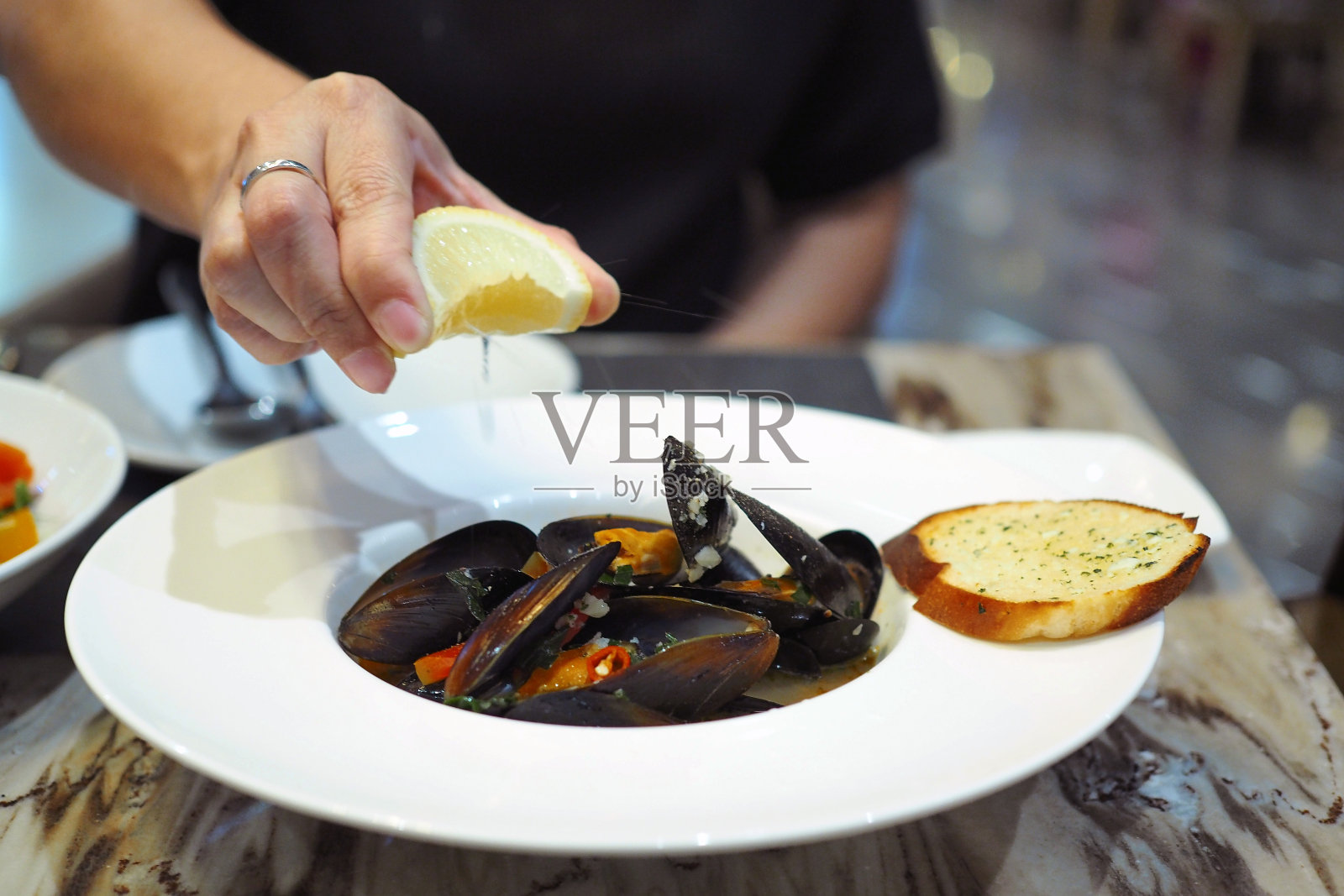 用白葡萄酒炒香辣青贻贝,将柠檬片挤在上面。照片摄影图片