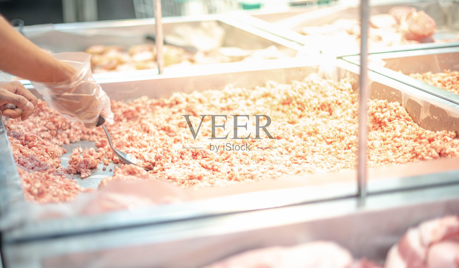 超市员工正在准备展示盘上的新鲜猪肉片供超市的消费者选择。照片摄影图片