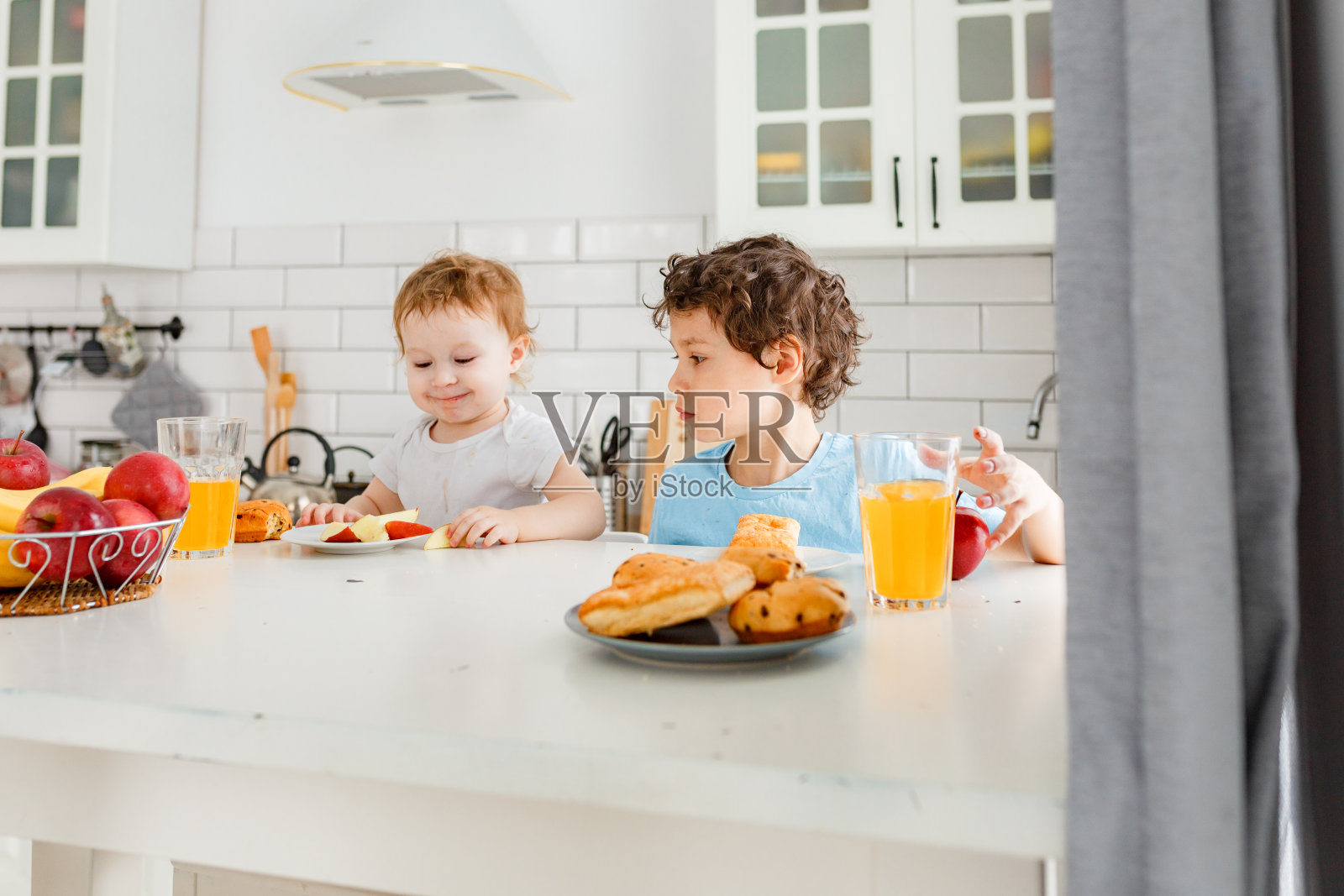 两个孩子真哥哥和真姐姐在明亮的厨房里吃着早餐照片摄影图片