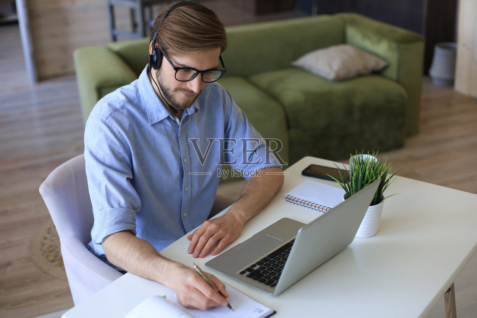 专注的年轻自由职业者商人使用笔记本电脑进行视频会议,在家远程在线工作。照片摄影图片