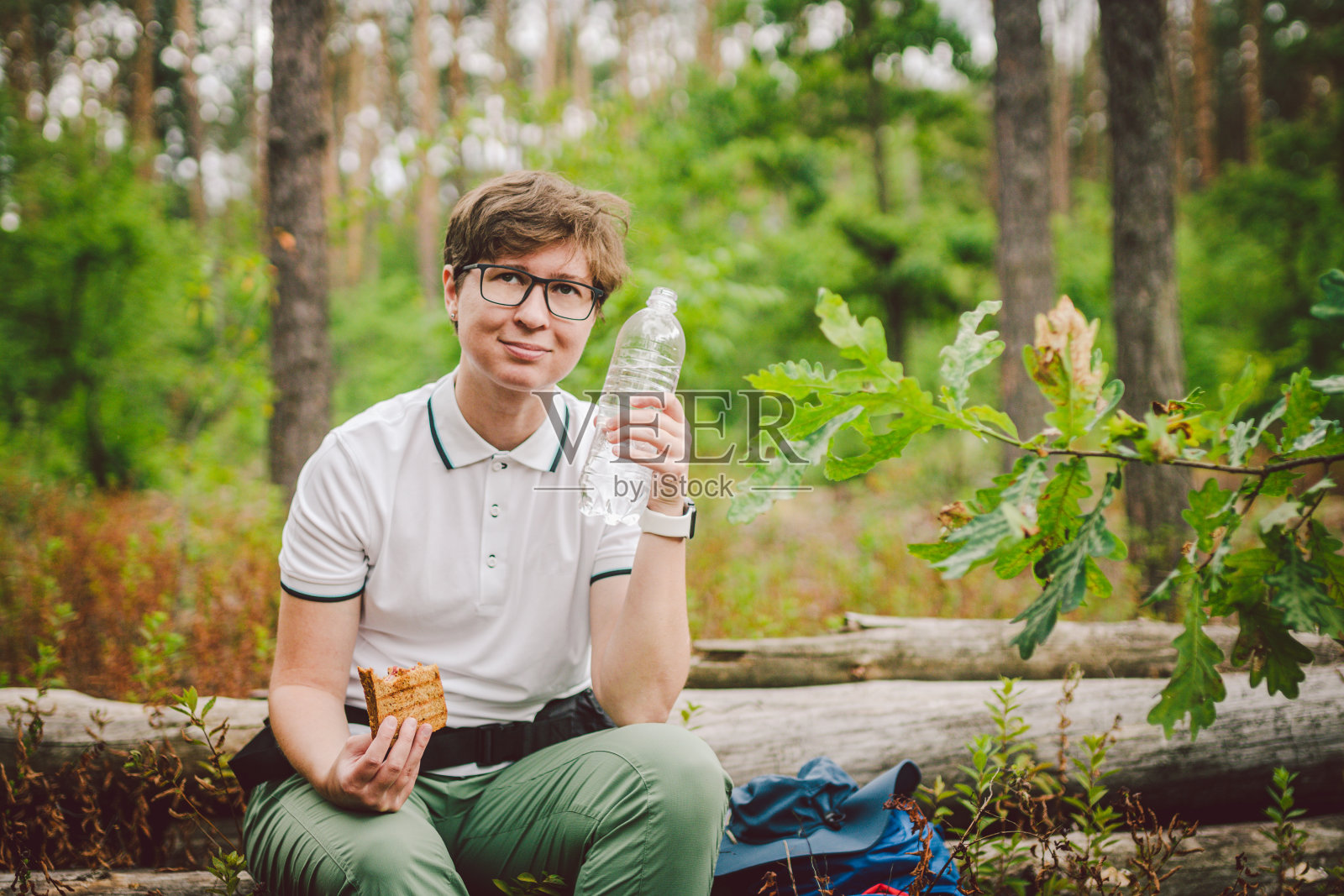 女性徒步旅行者在大自然中吃三明治。女游客有早餐或午餐在野餐,吃热三明治,而花时间在自然。旅行者停下来休息,吃着篝火烤三明治照片摄影图片