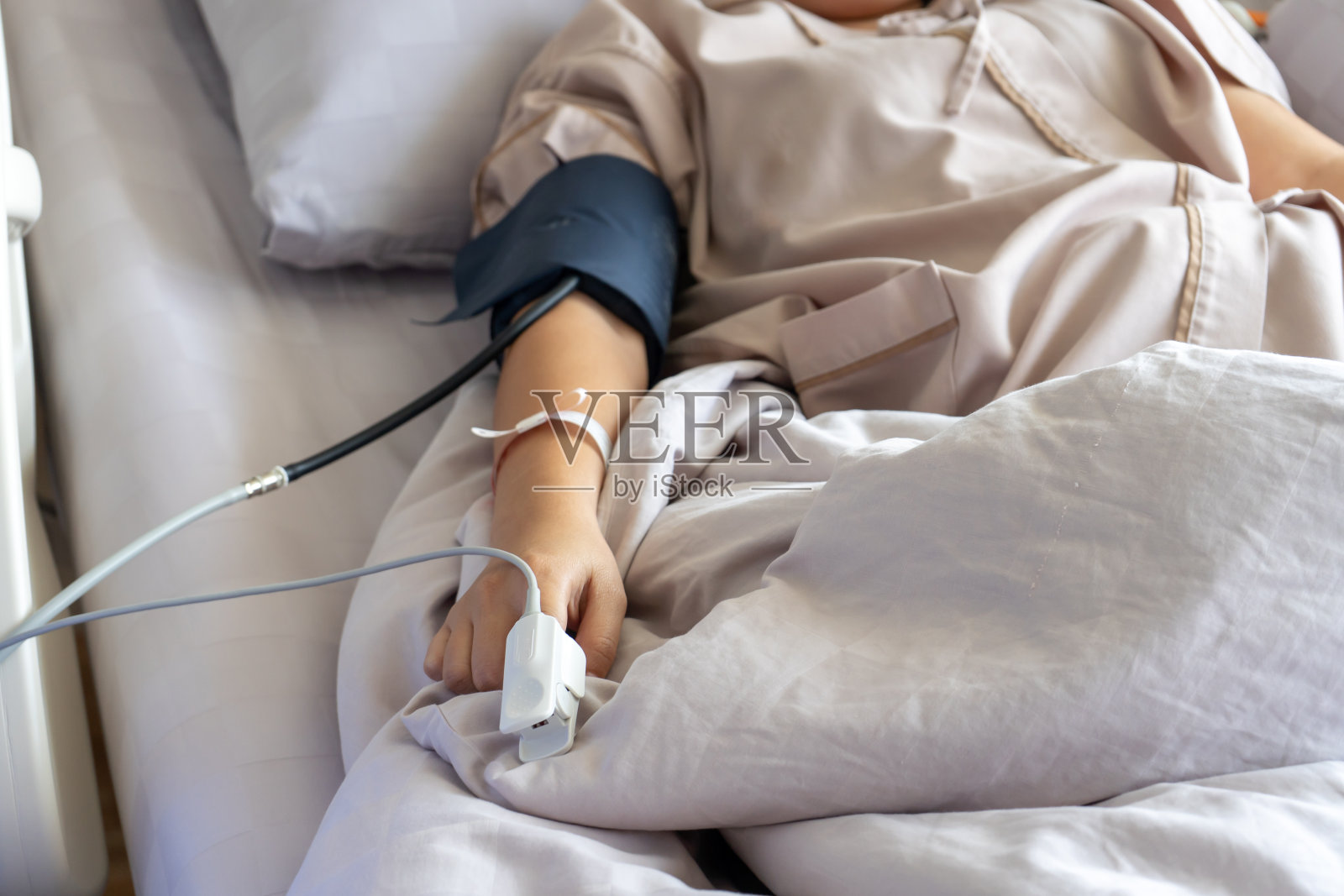 脉搏血氧计用于测量脉搏率和氧水平的一个病人,年轻女性的手指。病人在医院的病床上休息。照片摄影图片