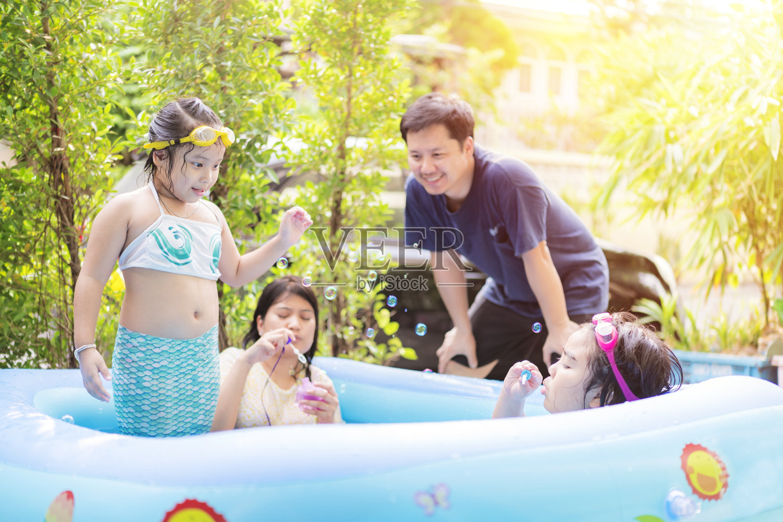 一个亚洲家庭在充气泳池里玩照片摄影图片