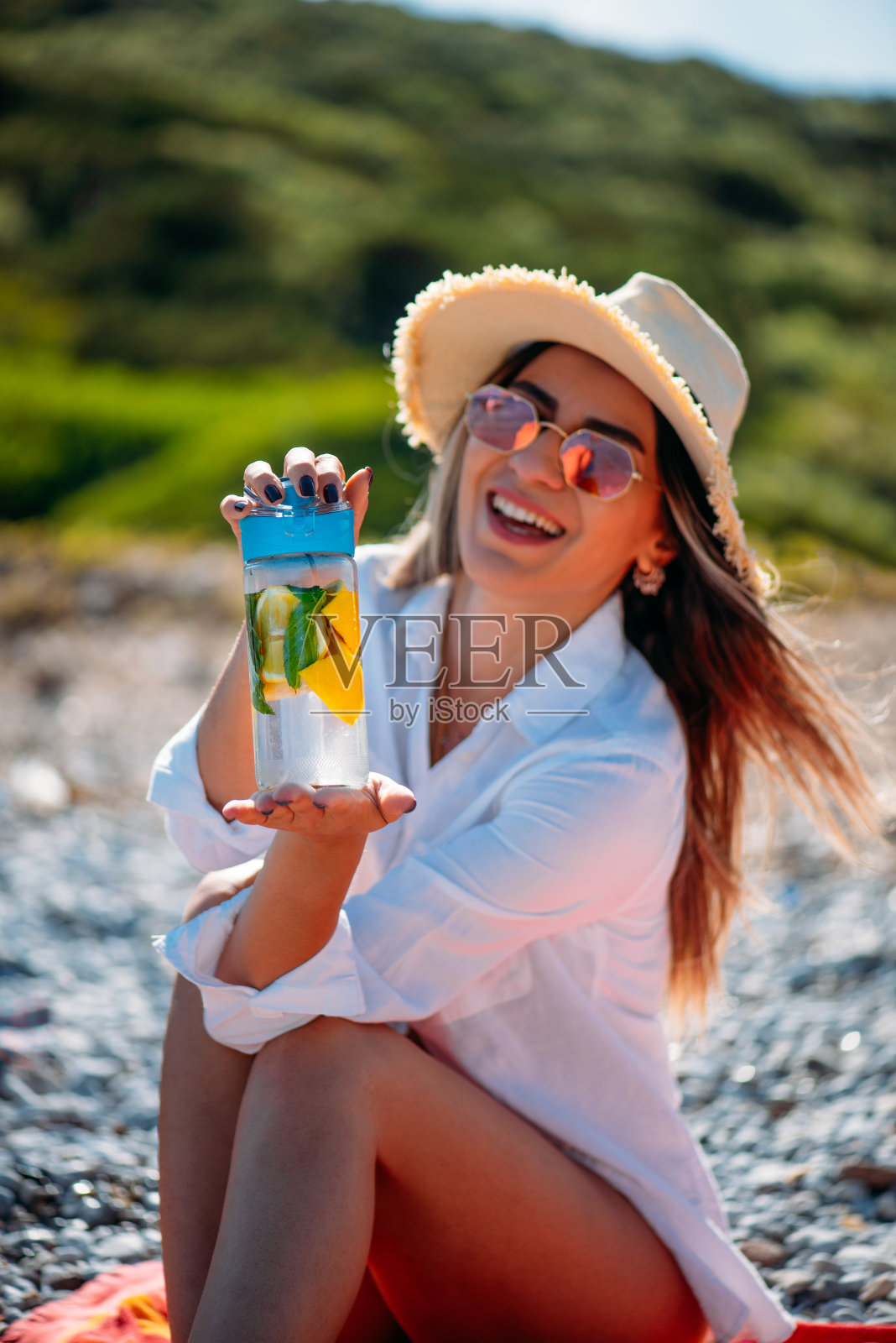 可爱的女人在海滩上喝排毒水照片摄影图片