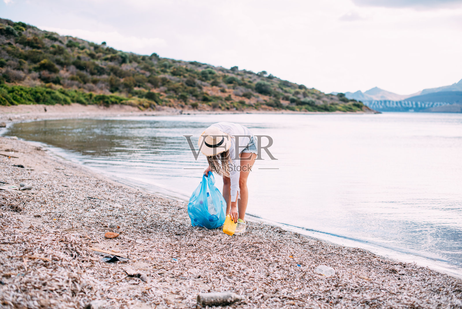 在海滩上捡垃圾的女人照片摄影图片