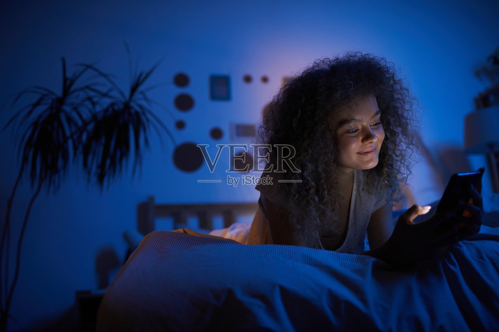 微笑的女人在晚上使用智能手机照片摄影图片