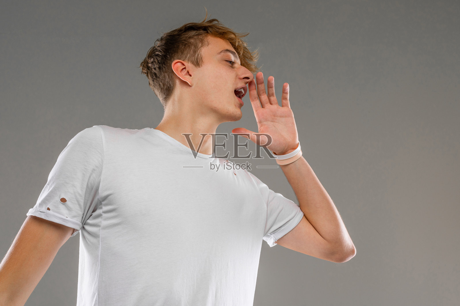 年轻的白人男子在白色t恤摆姿势和手势在相机孤立的灰色背景照片摄影图片