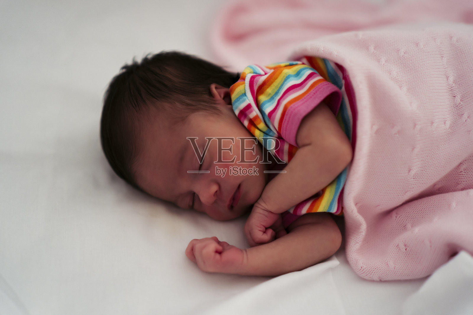 刚出生的婴儿睡在他的婴儿床里照片摄影图片