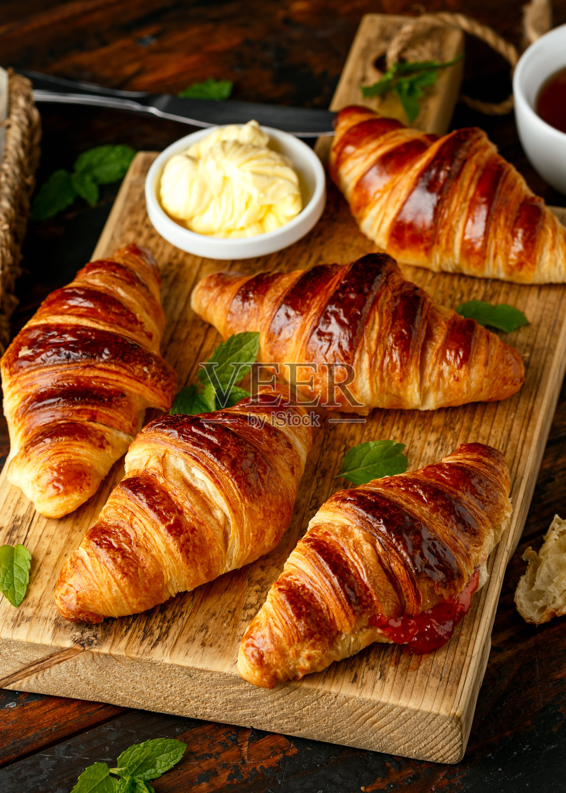 新鲜烤牛角面包配黄油,草莓酱和茶作为早餐或早午餐照片摄影图片