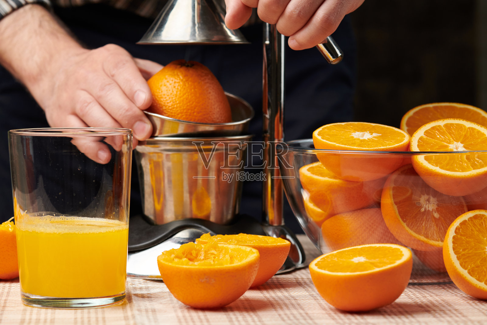 用手动压榨机压榨橙子,近距离观察,制作一杯新鲜的橙子。新鲜的橙子放在木桌上,整只,榨干,切成片。照片摄影图片