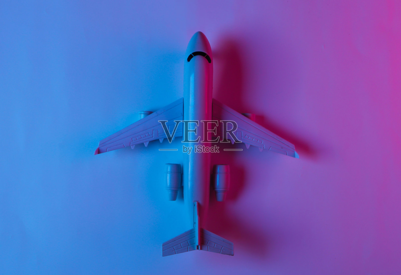 霓虹蓝粉灯光的飞机小雕像。俯视图照片摄影图片