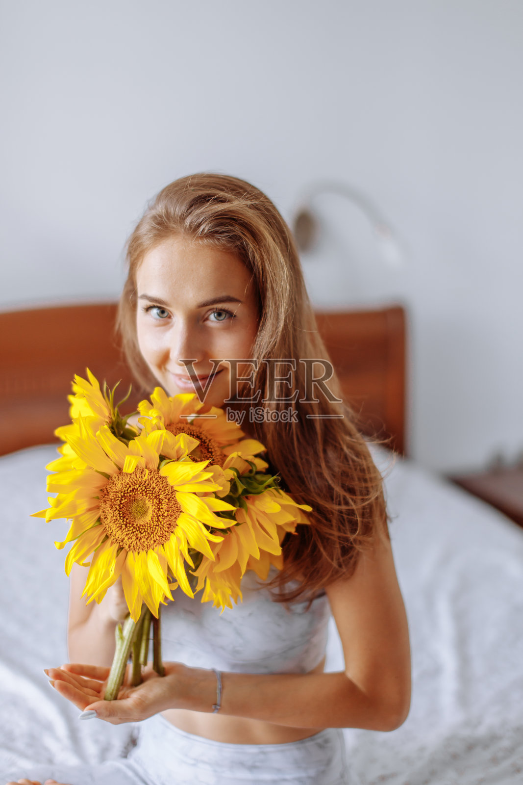 年轻的瑜伽女在家里的床上和向日葵照片摄影图片