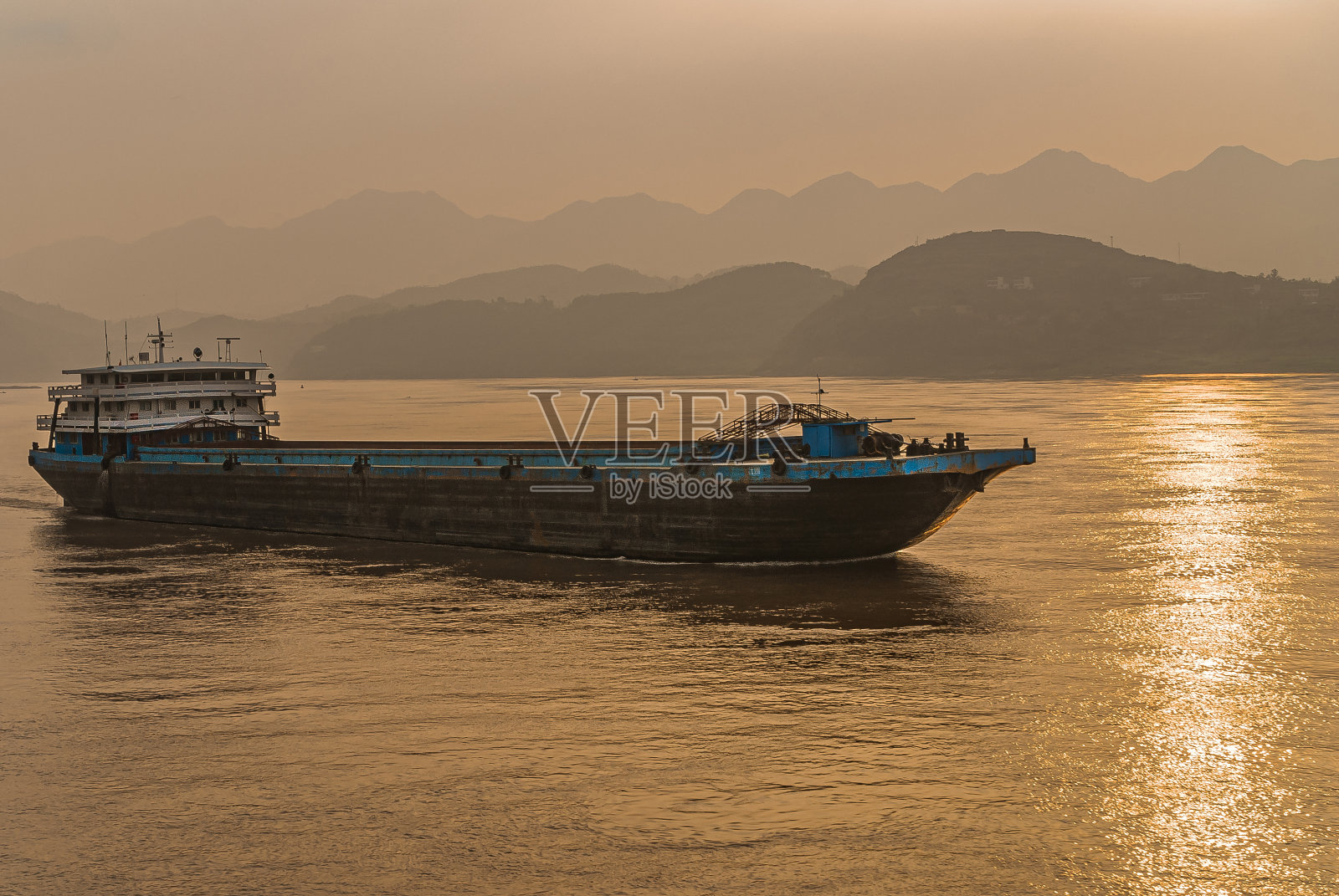 中国重庆,驳船扬帆而行,夕阳映在长江上。照片摄影图片