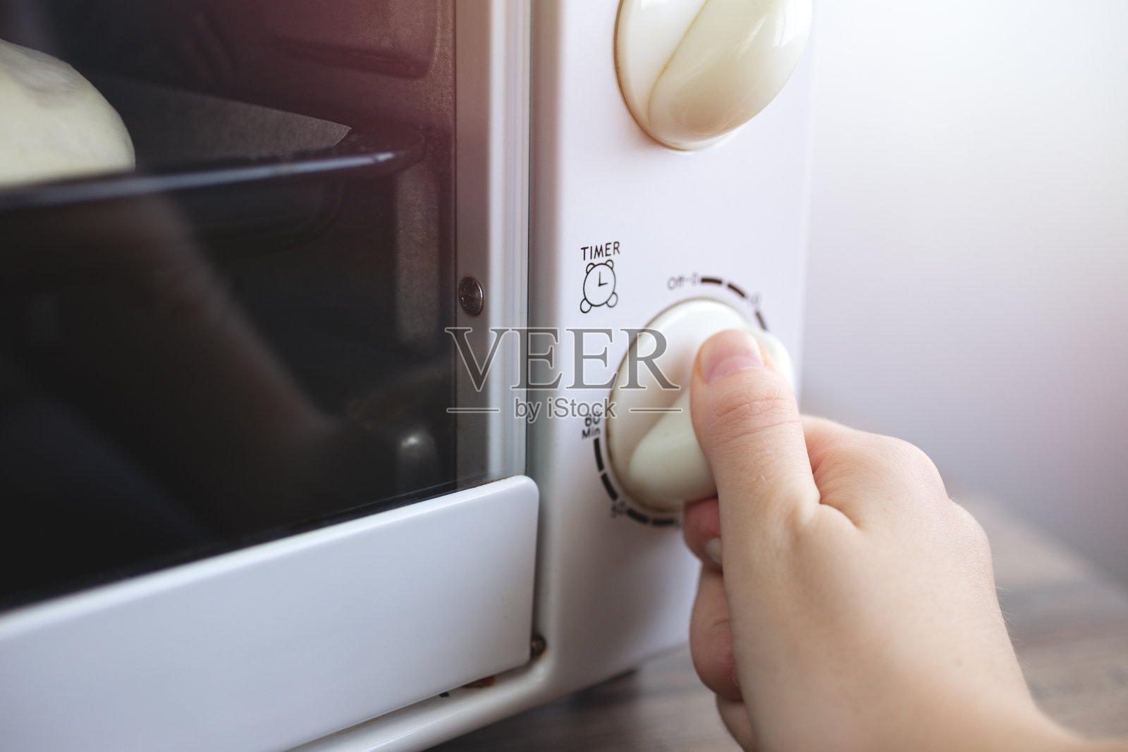 近景手动旋转设定定时器的背景微波炉。家庭烹饪或食物准备的概念照片摄影图片