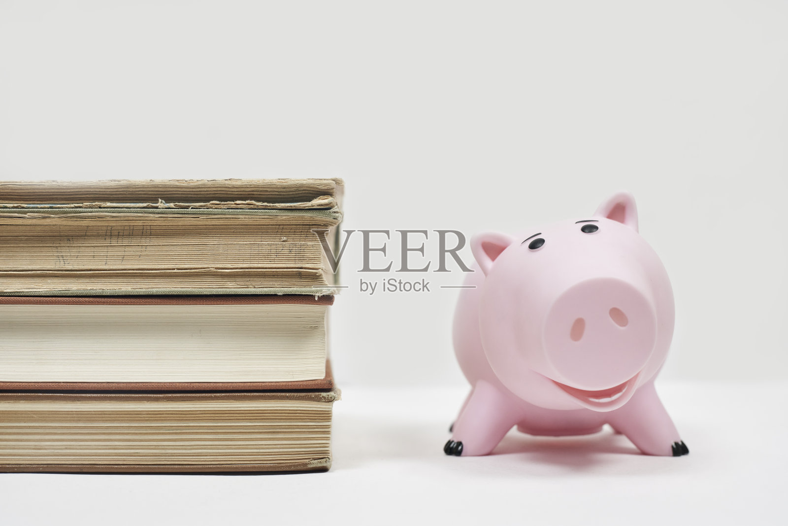 叠旧书和存钱罐。教育的成本。为上大学存钱。为孩子上大学攒钱照片摄影图片