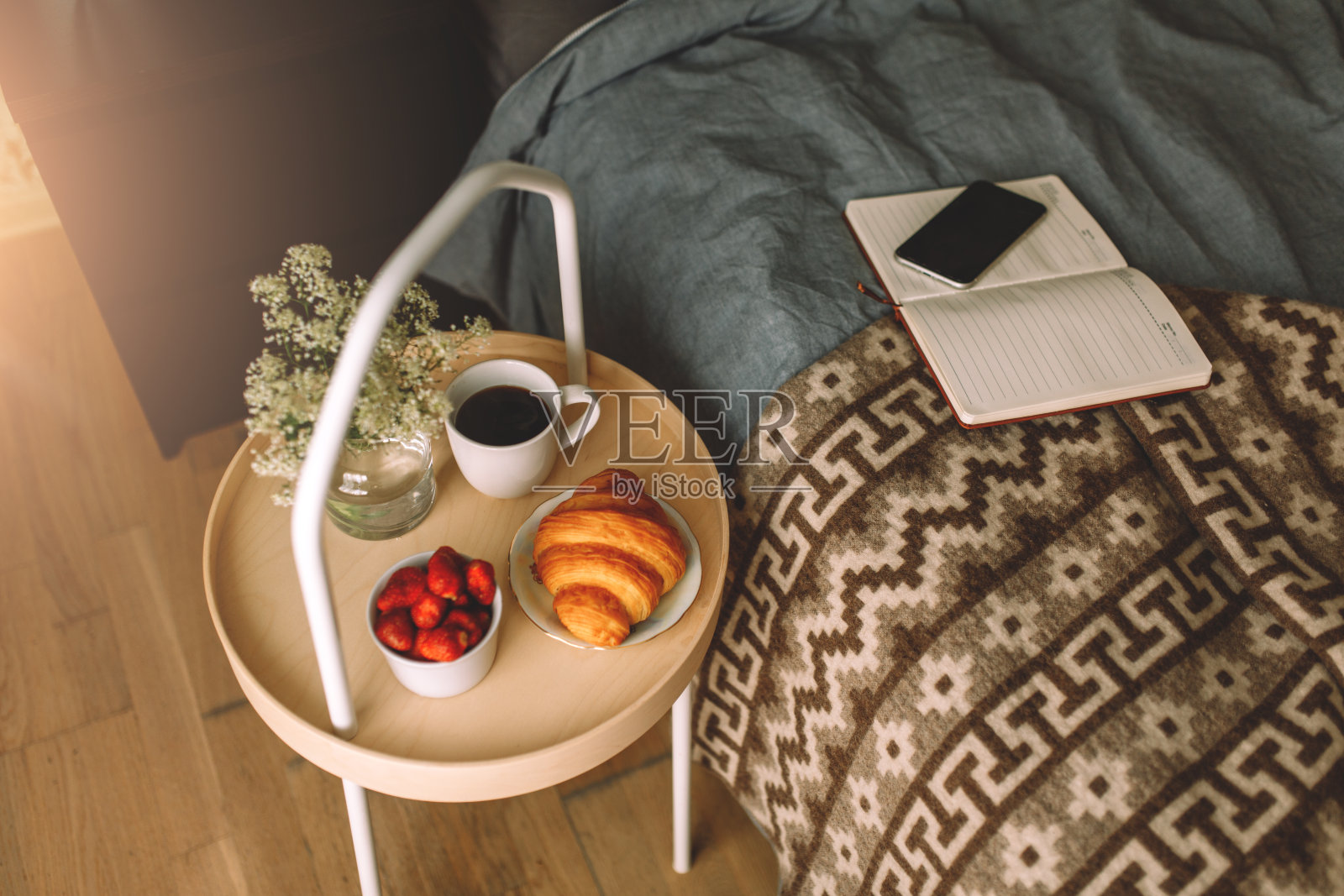 早餐放在家里床上的托盘上,又白又黑的亚麻布。羊角面包茶草莓照片摄影图片