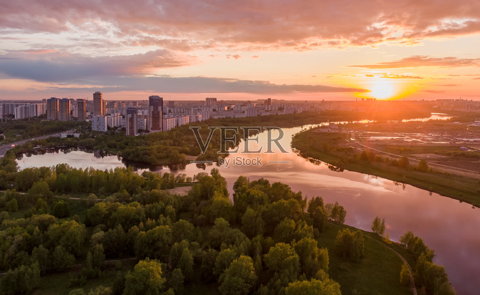美丽的晚霞映衬着河边的城郊,在画面中勾勒出自然和流水。航空摄影照片摄影图片