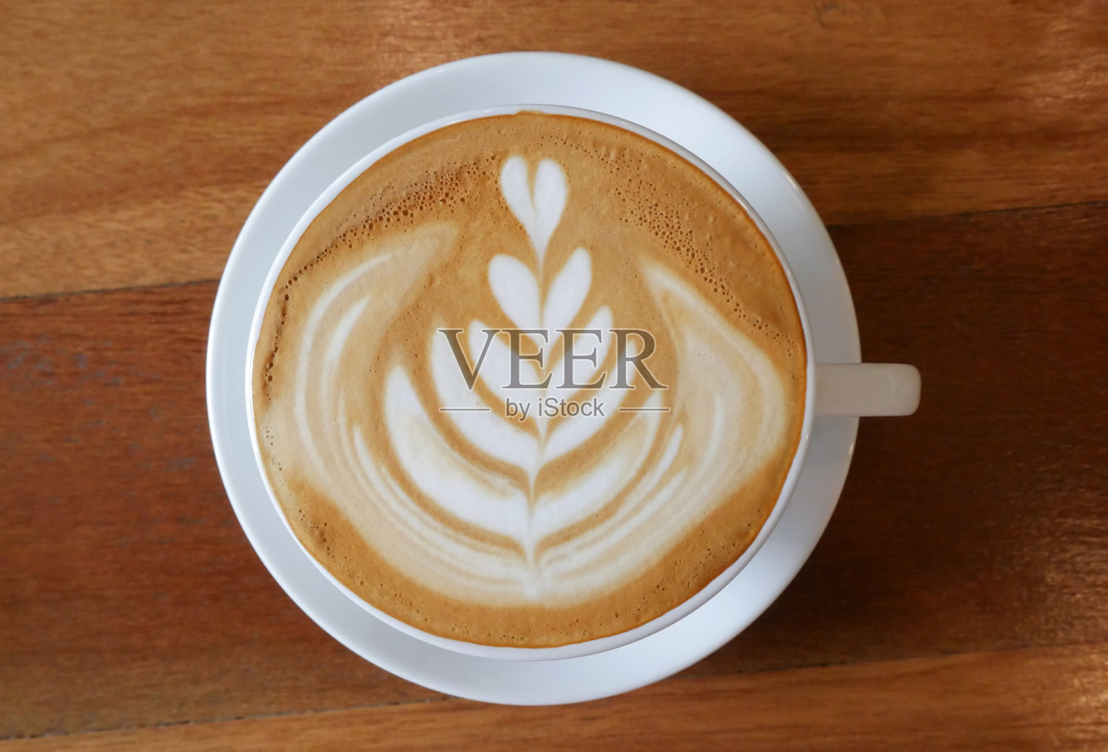顶视图热咖啡卡布奇诺拿铁艺术花形状在陶瓷杯上木制桌子的背景照片摄影图片