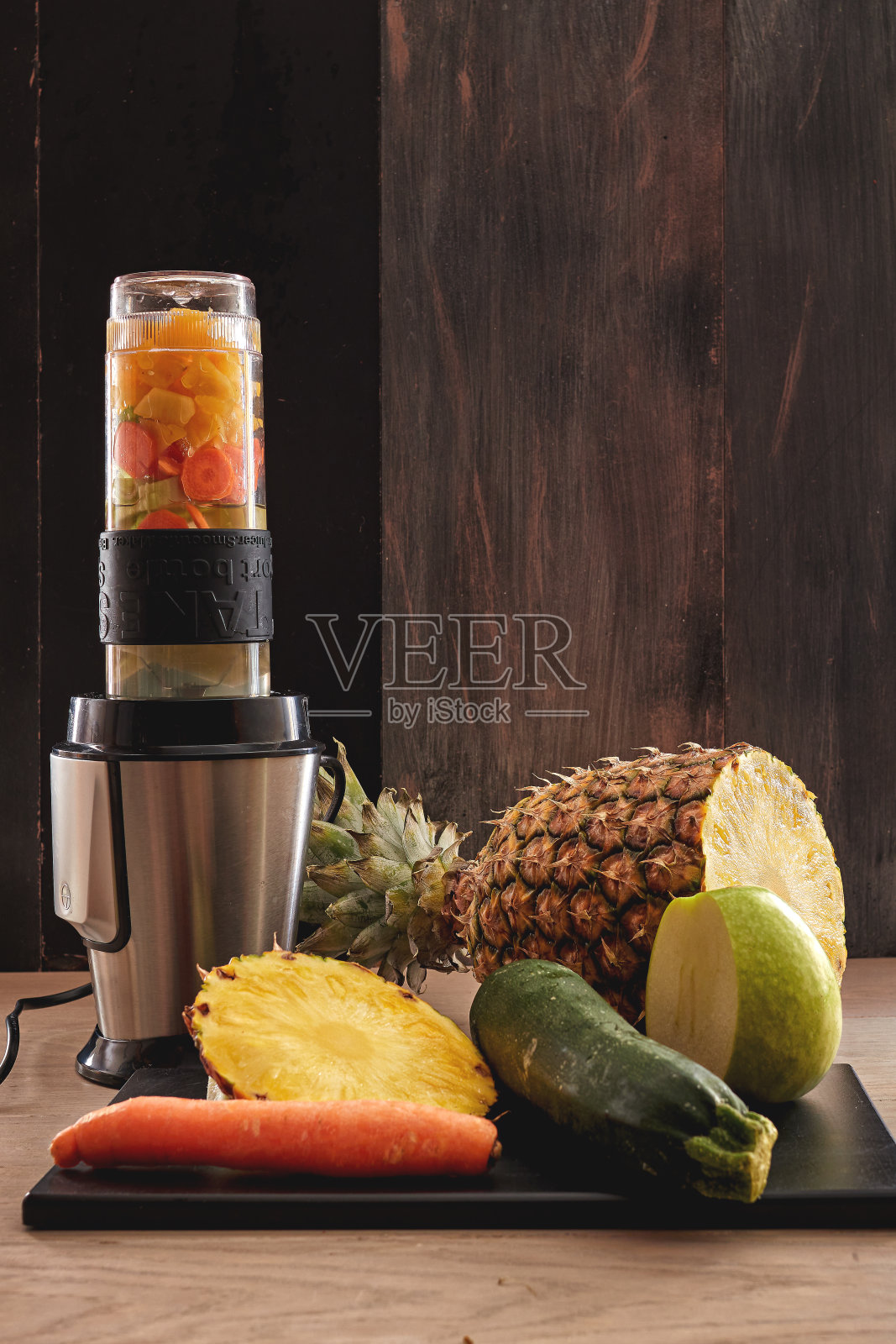 用菠萝、苹果、黄瓜和胡萝卜混合在一起做成的蔬菜汁照片摄影图片