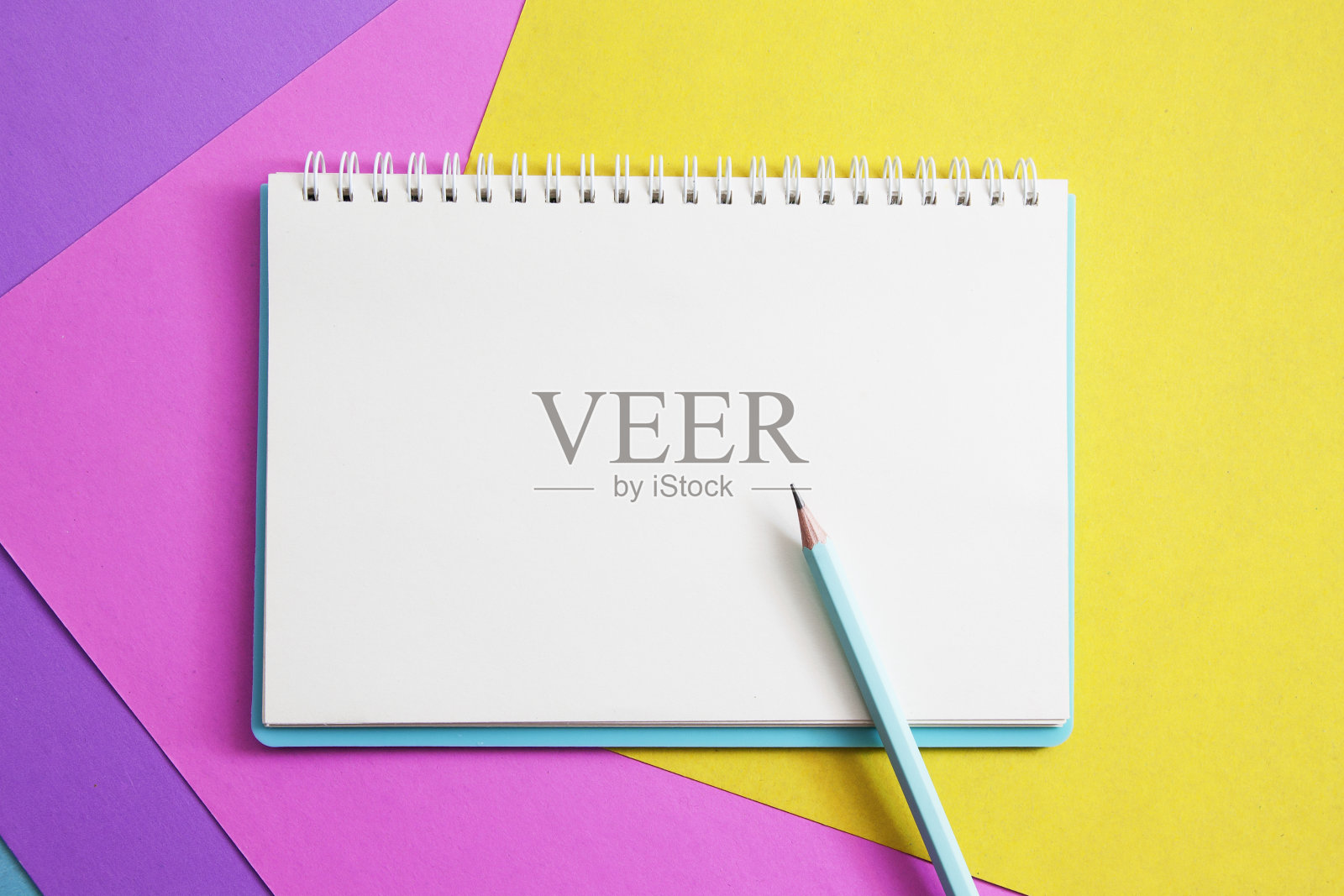 用白纸和铅笔在彩色纸上的记事本。模拟你的文本。照片摄影图片