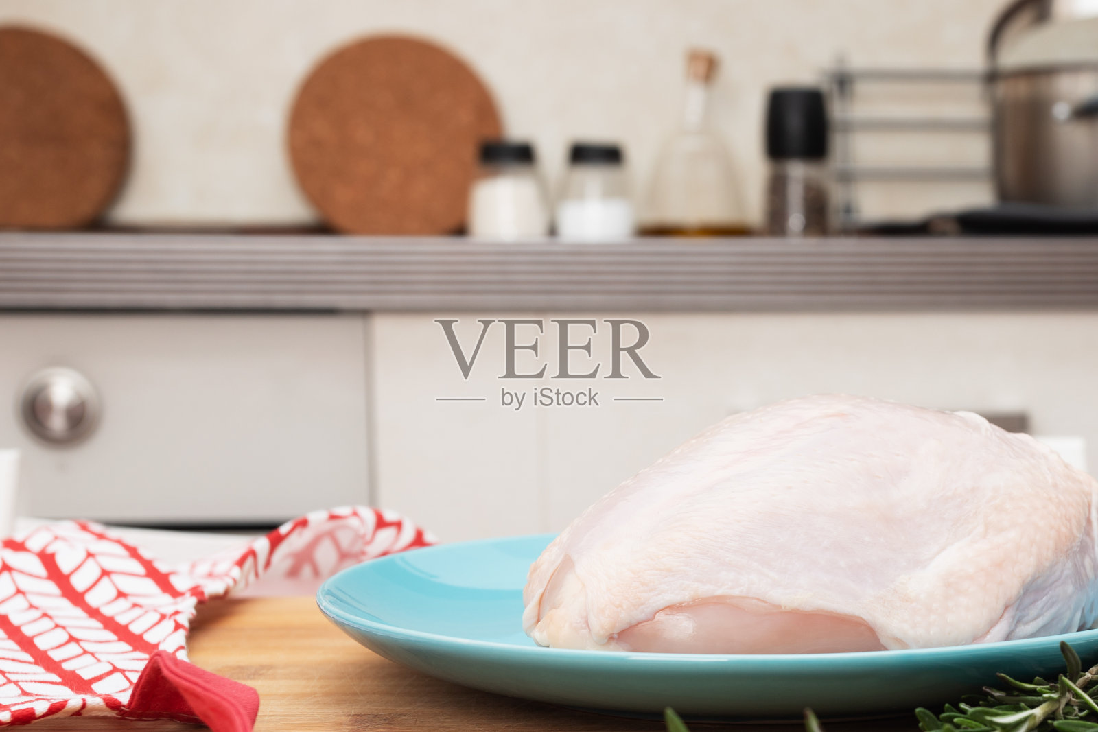 在烹饪前,生鸡胸肉放在厨房桌子上的蓝色盘子上照片摄影图片