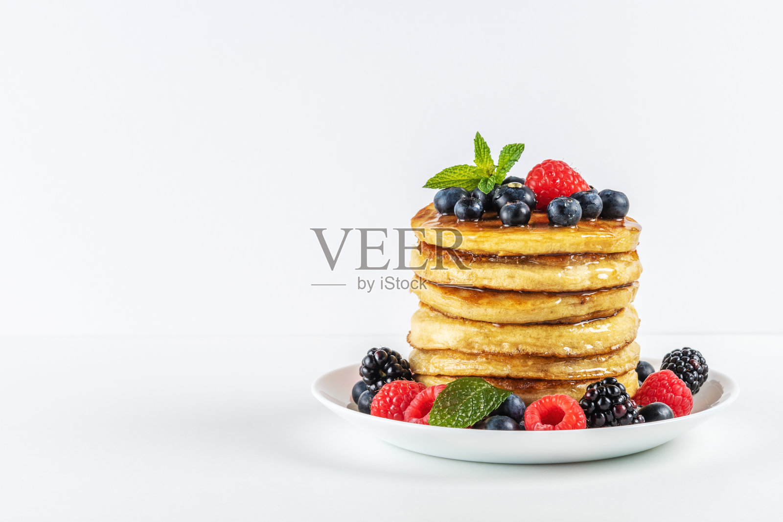 美味的煎饼和新鲜的浆果放在白色的桌子上。食品的概念。照片摄影图片