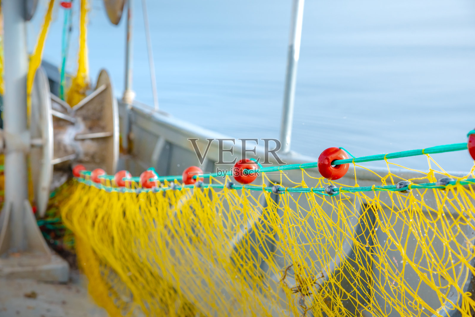 希腊克里特岛的渔船上,渔民正在用黄色的渔网捕捞新鲜的鱼。照片摄影图片