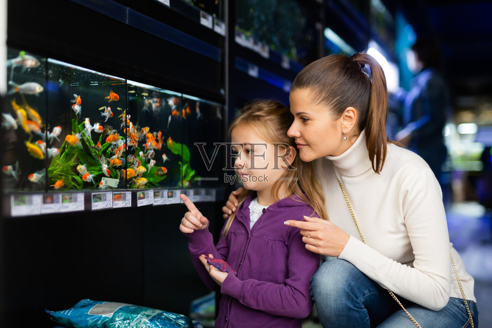 女孩和妈妈在宠物店选择水族鱼照片摄影图片
