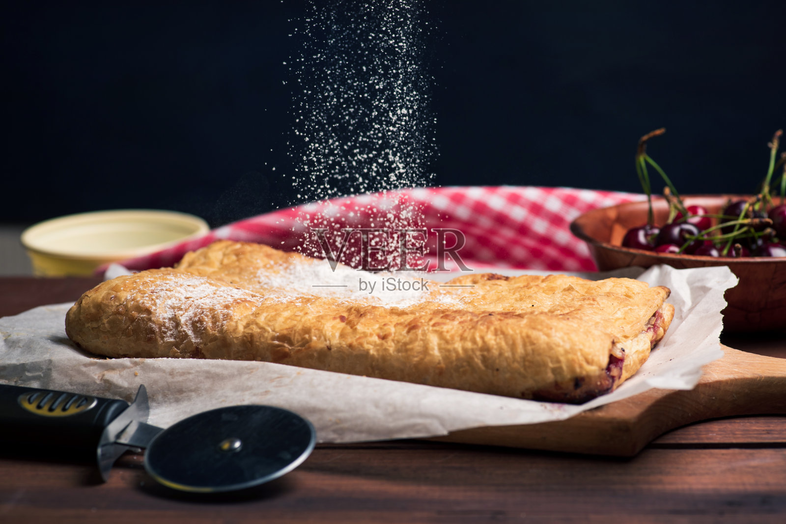 糖落在切菜板上的甜樱桃派上照片摄影图片