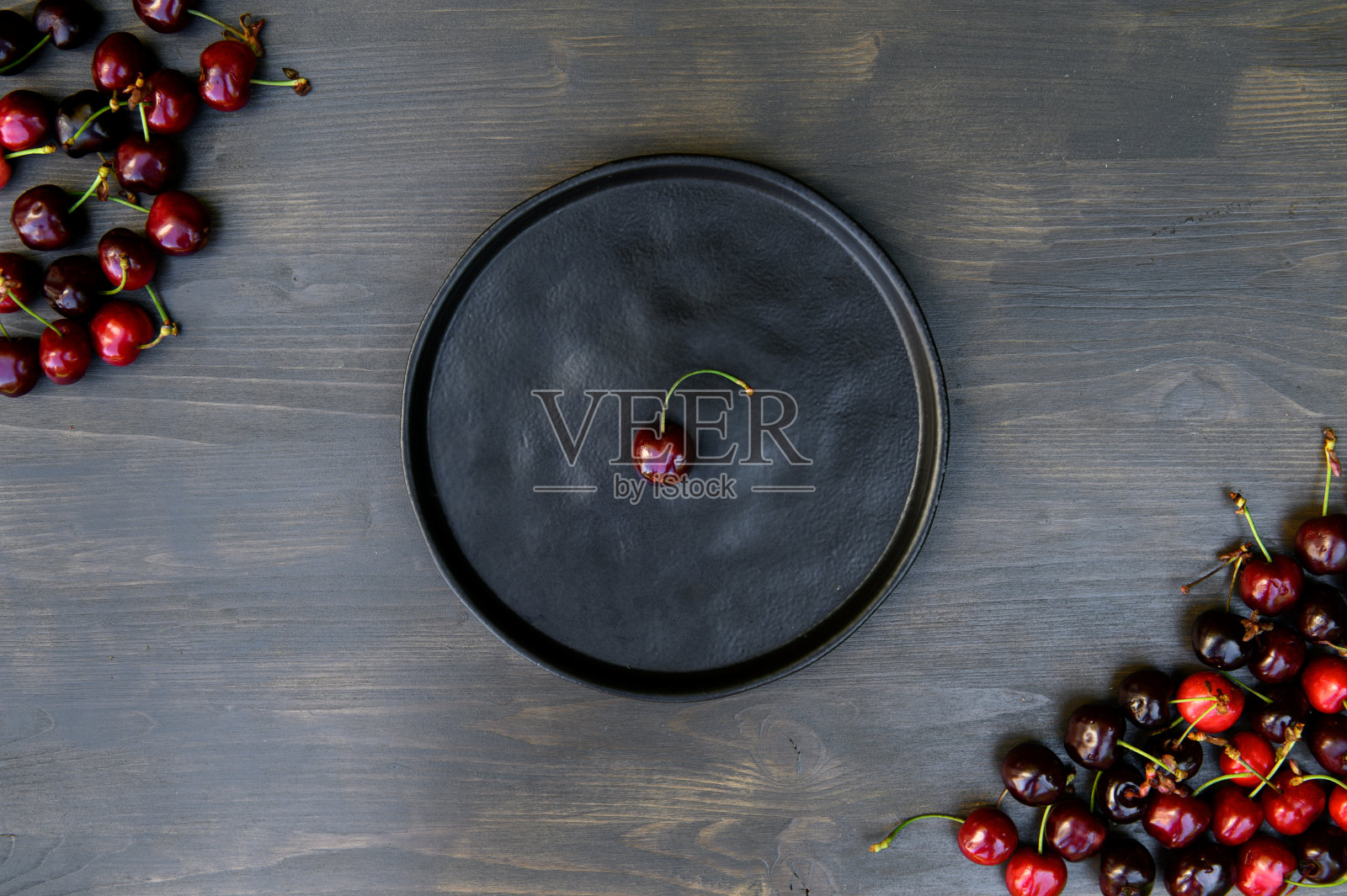 多汁的,成熟的,美丽的甜樱桃在陶瓷黑色盘子上,木制的背景。照片摄影图片