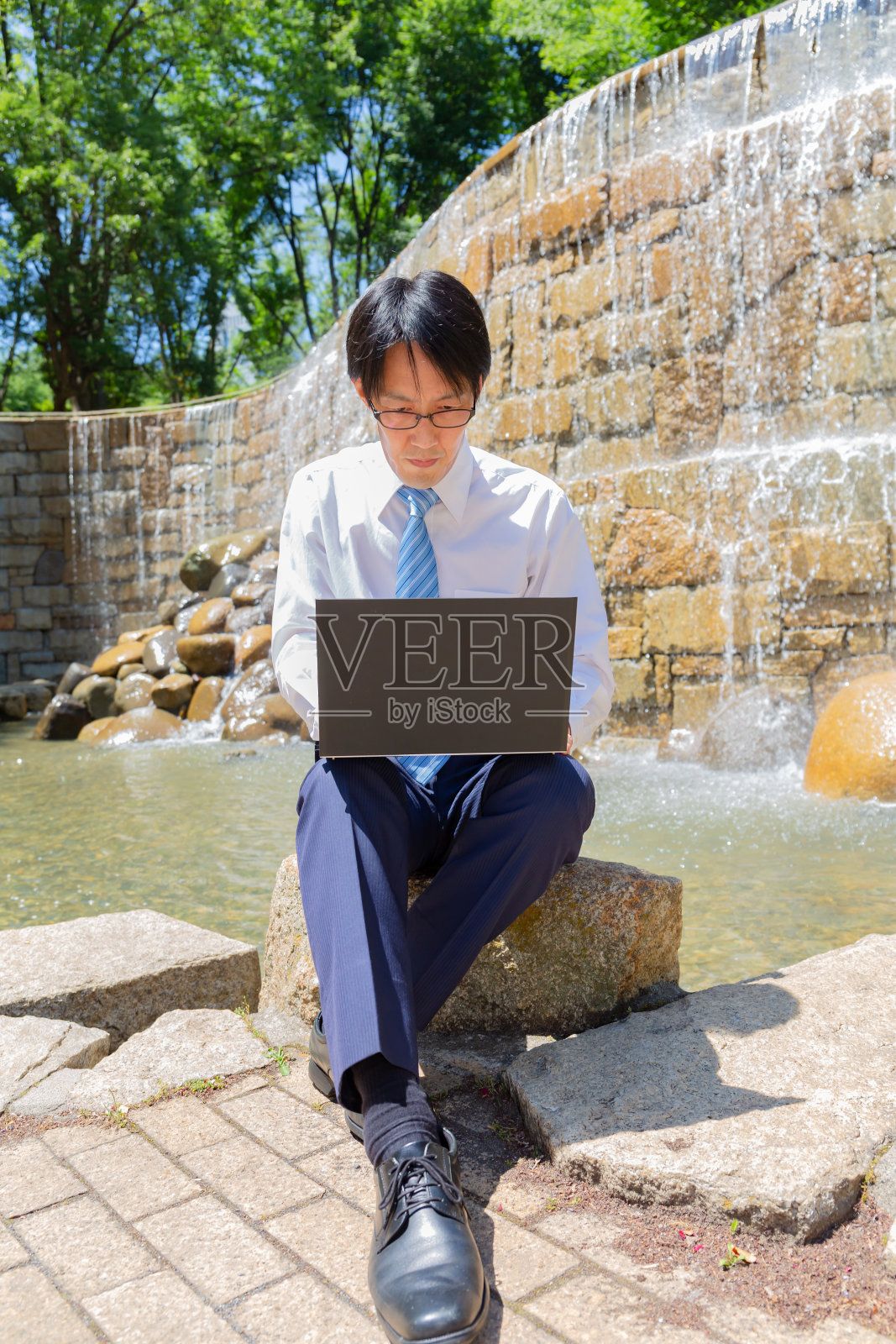 在水边操作电脑的日本男子照片摄影图片