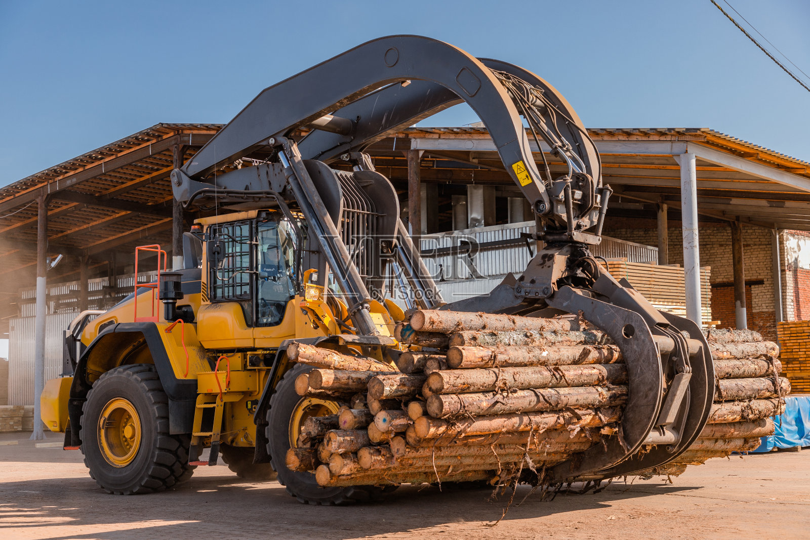 原木装载设备。原木装载机的木材,原木。原木装载器移动一堆松木。木材行业。木工工厂。照片摄影图片