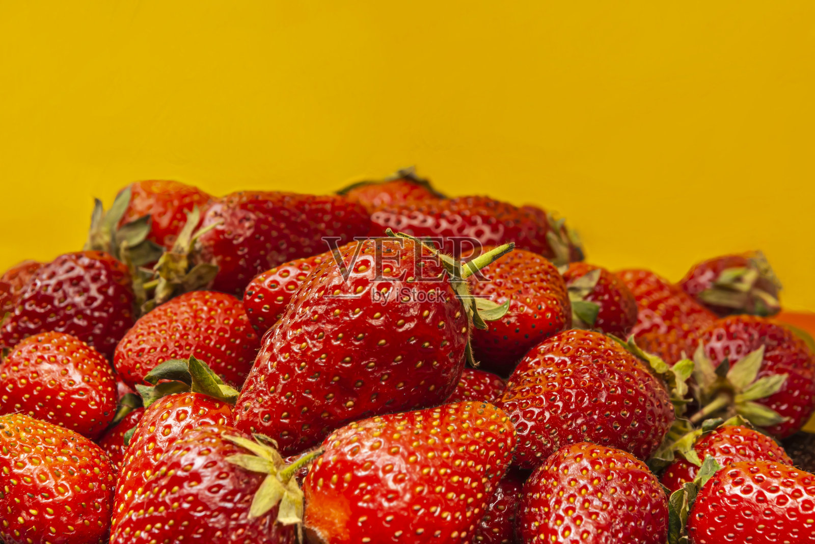 新鲜美味的草莓在黄色的背景。夏天的时间概念照片摄影图片