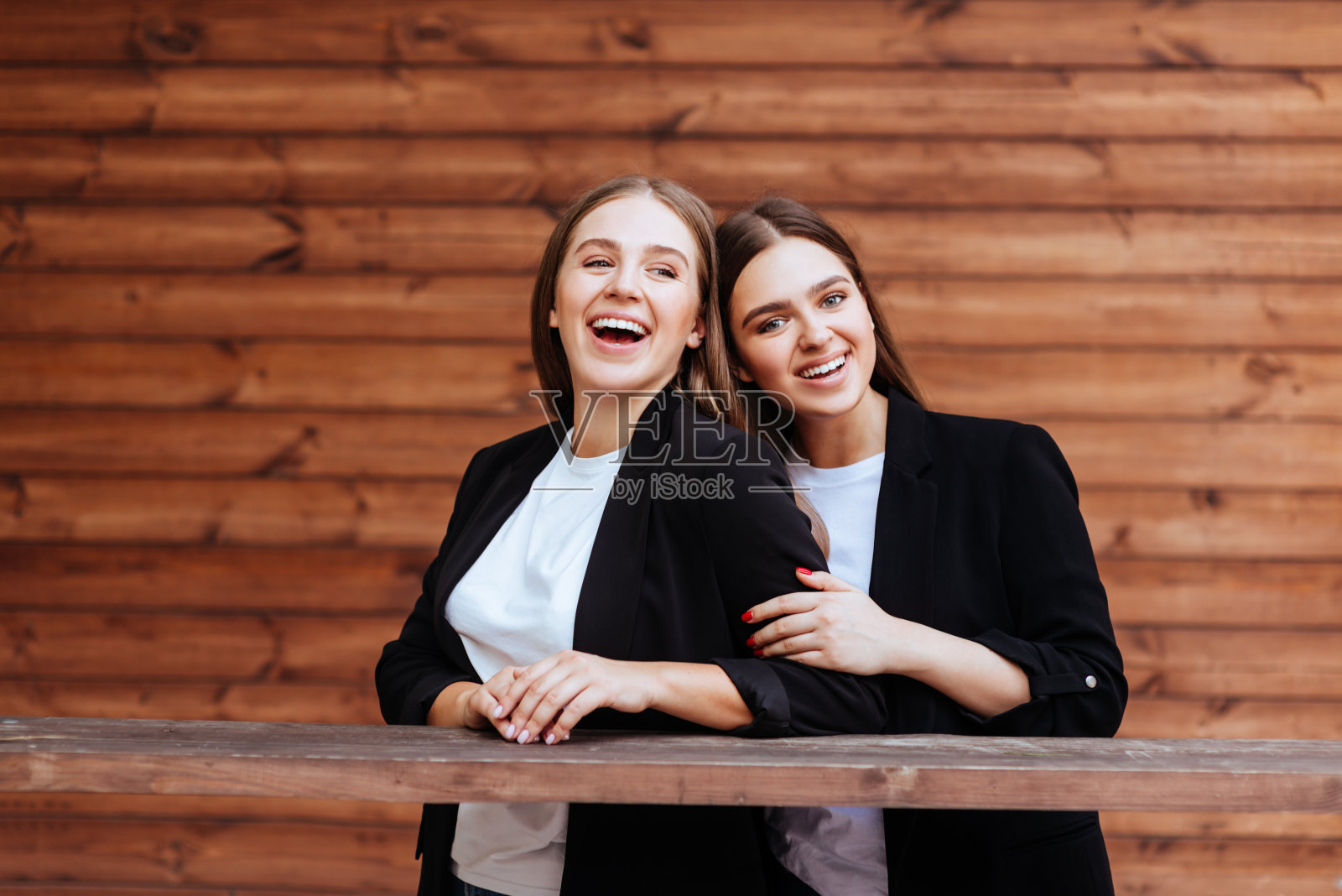 两个迷人的年轻女孩站在一起,在镜头前摆姿势。照片摄影图片