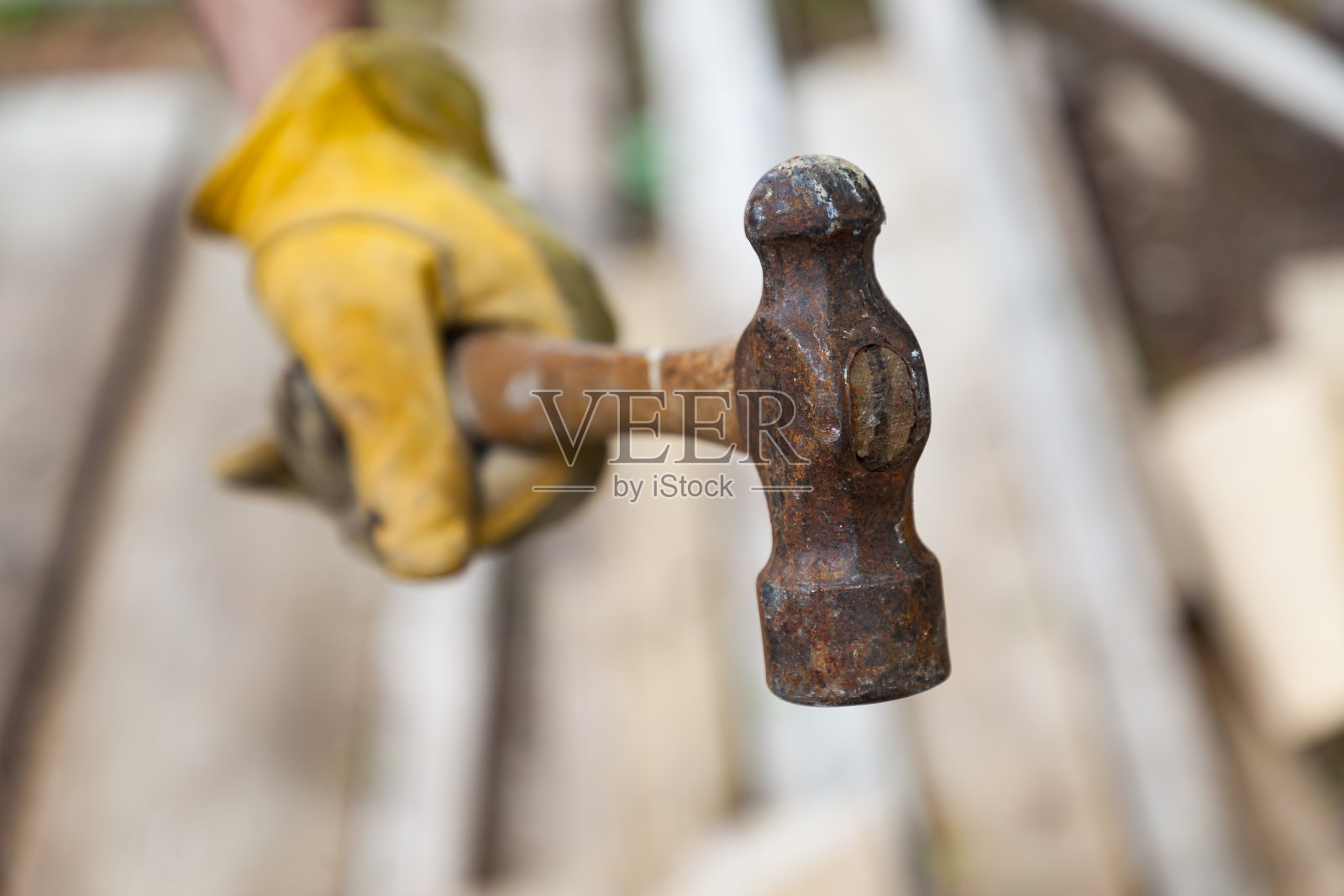 一个戴着黄色工作手套的人手里拿着一把锤子照片摄影图片