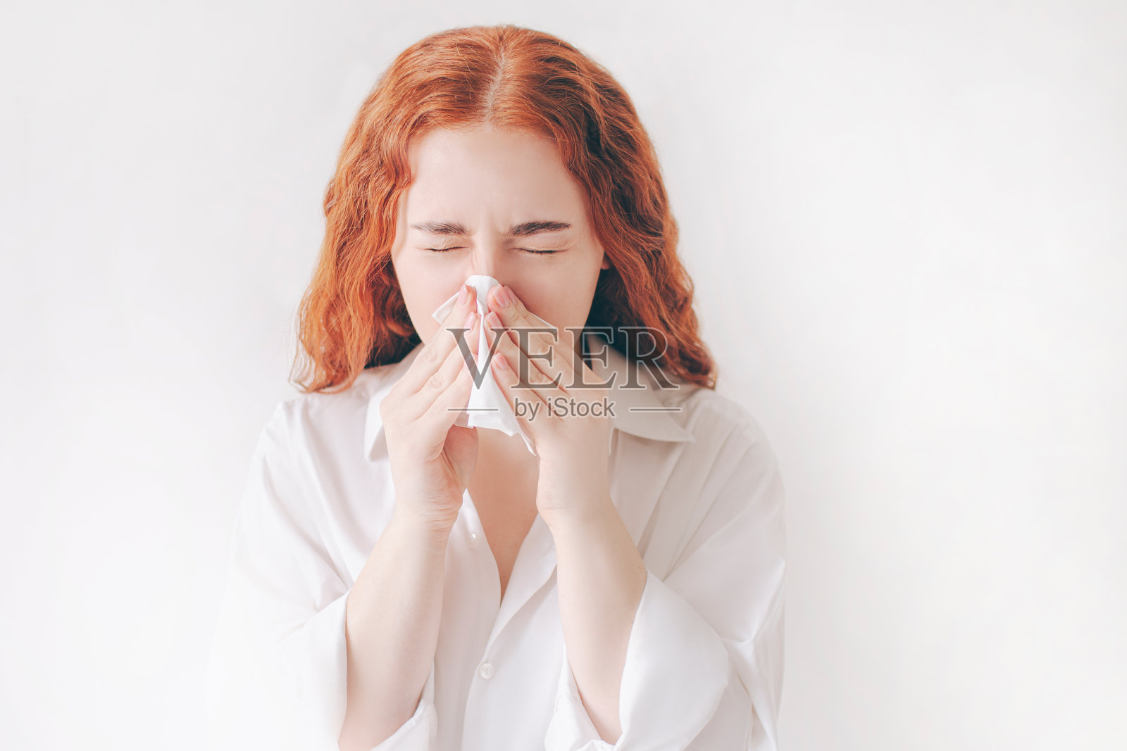 年轻女子用手帕。生病的女孩流鼻涕。女模特使治疗普通感冒孤立在白色的背景照片摄影图片