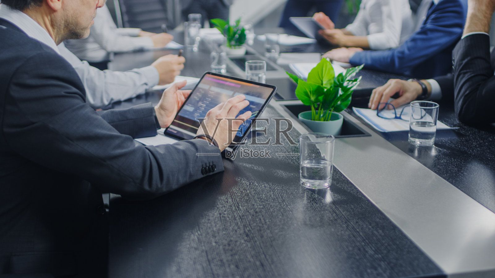 在企业会议室,商务人员手中的特写,与使用数字平板电脑签订合同。坐在会议桌前的人照片摄影图片