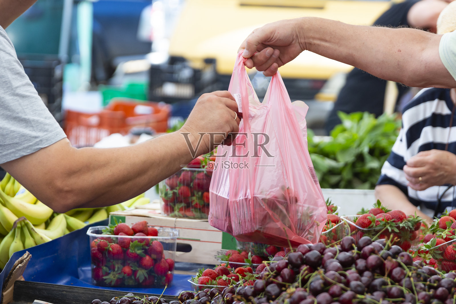 人们在街头市场买新鲜的有机草莓。卖装在塑料袋里的水果和蔬菜,付钱照片摄影图片