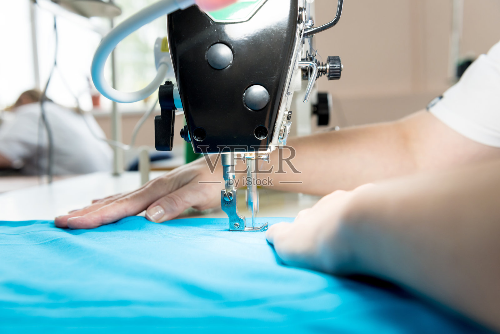 设计师裁缝缝制连衣裙。女人用缝纫机干活。照片摄影图片