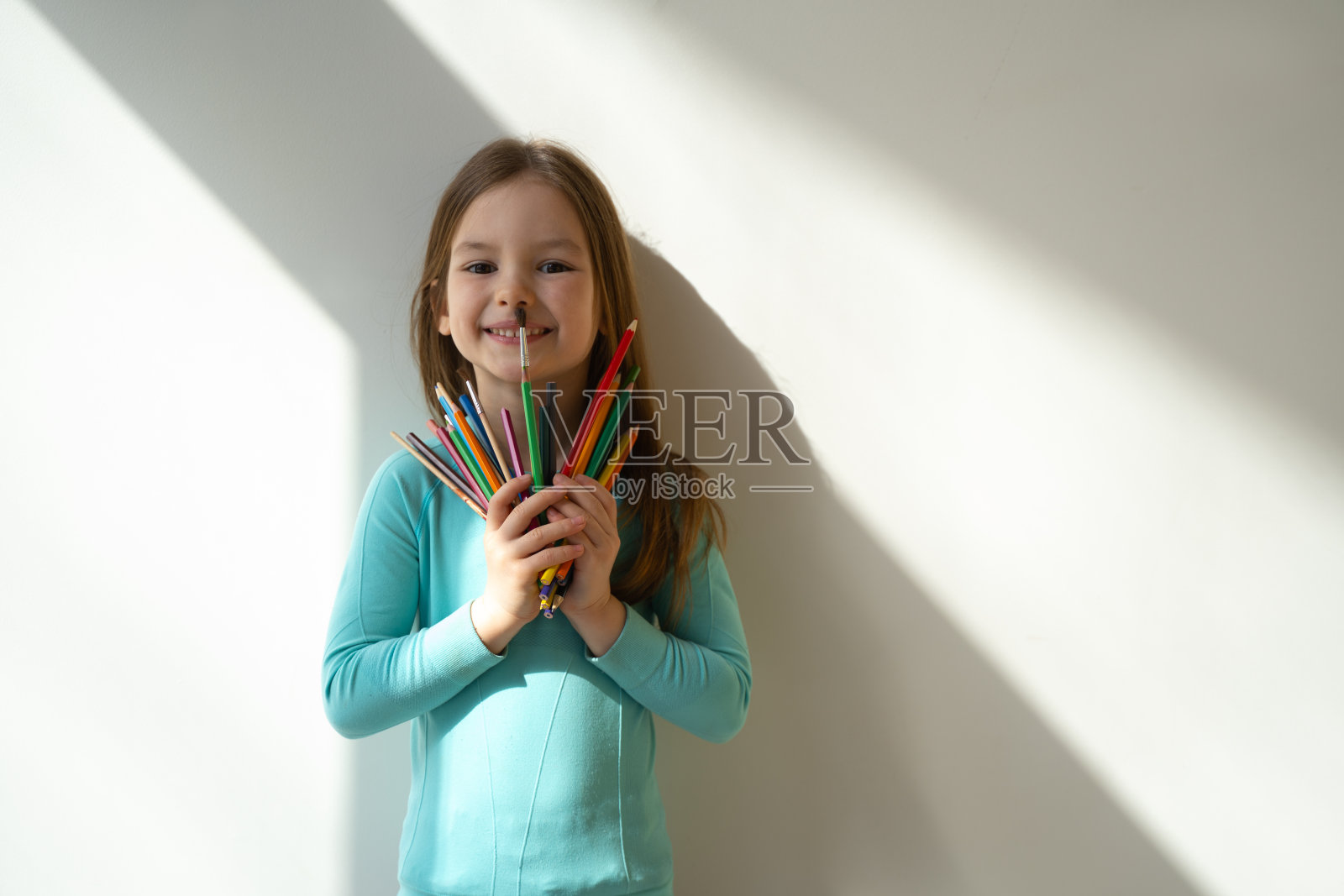 快乐的小女孩拿着彩色铅笔和画笔照片摄影图片