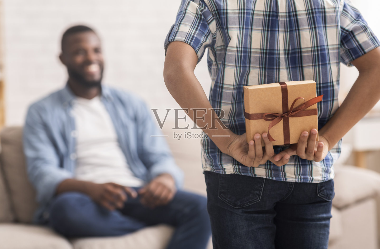 男孩用父亲节问候父亲,把礼物藏在背后照片摄影图片