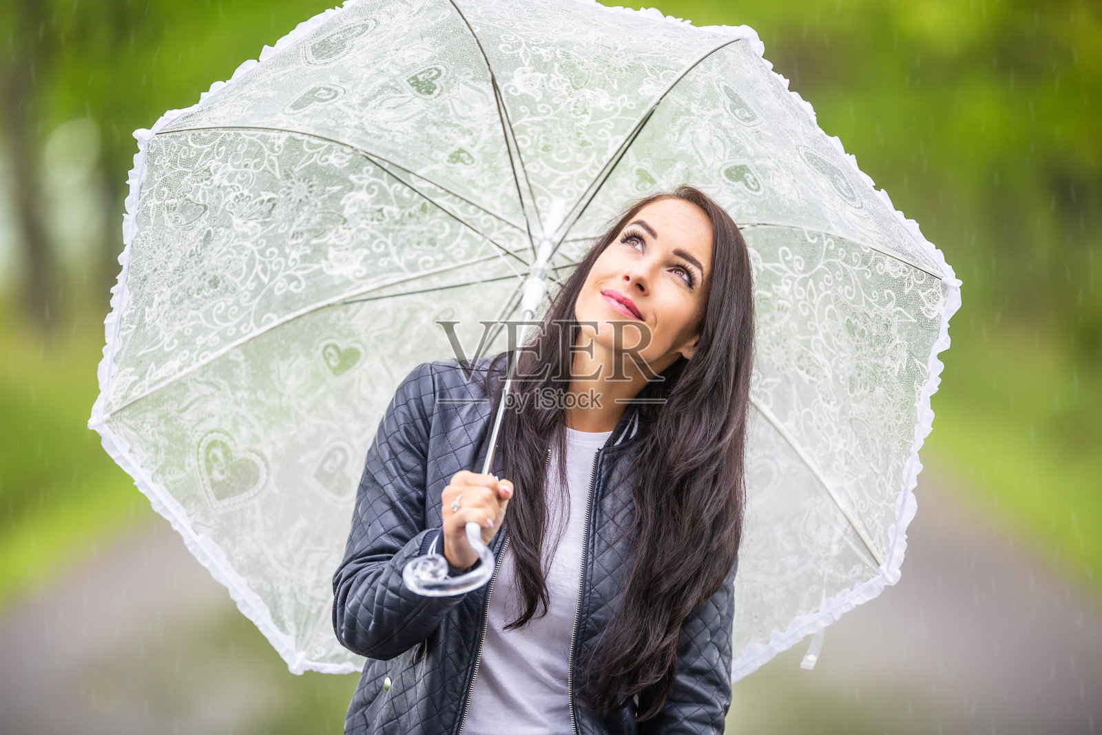 在大自然中散步时,一个漂亮的女孩肩上撑着一把伞,仰望天空。照片摄影图片