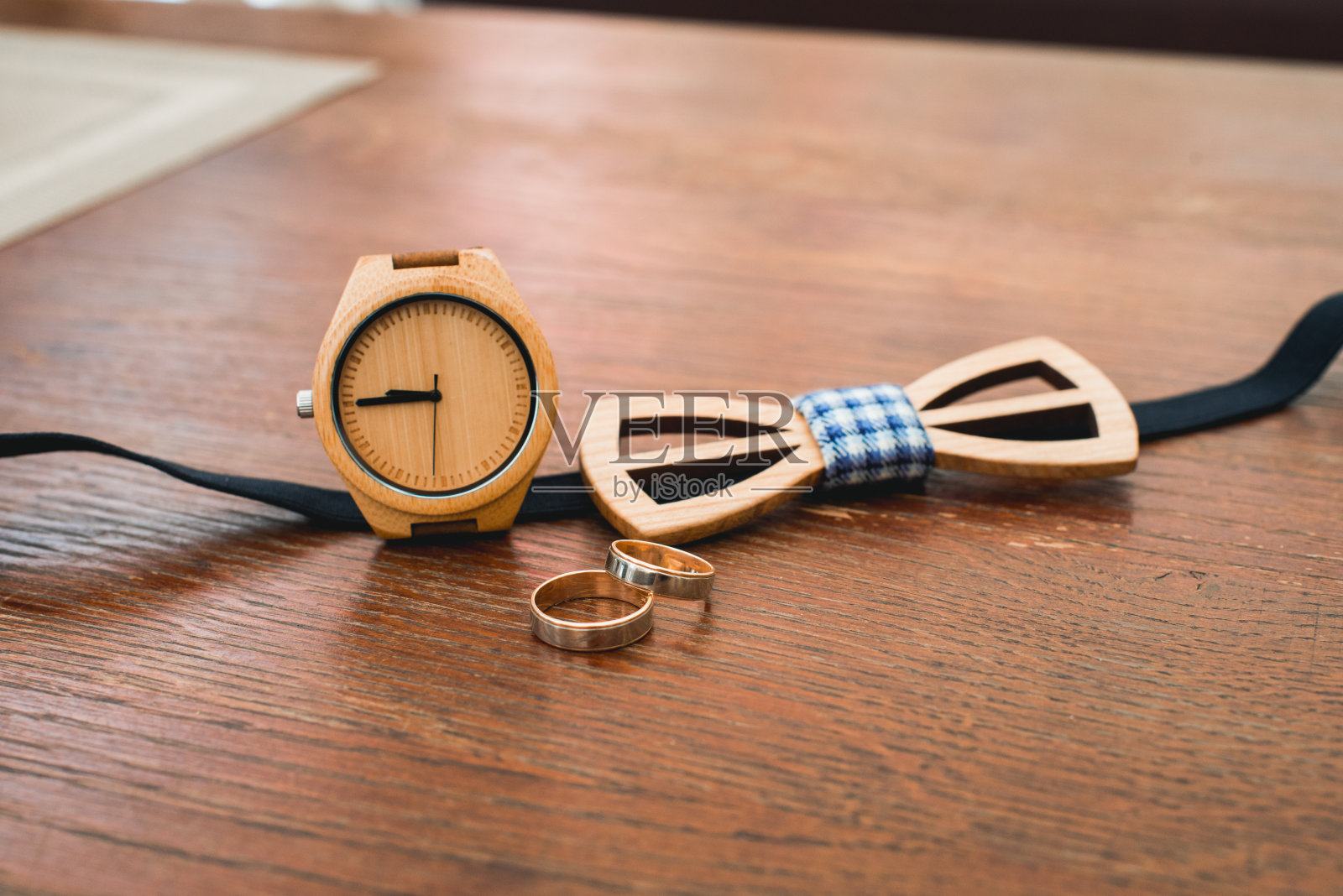 时尚的木质手表和领结的新郎在酒店房间的桌子上。婚礼前的早晨准备。男士奢饰品。照片摄影图片