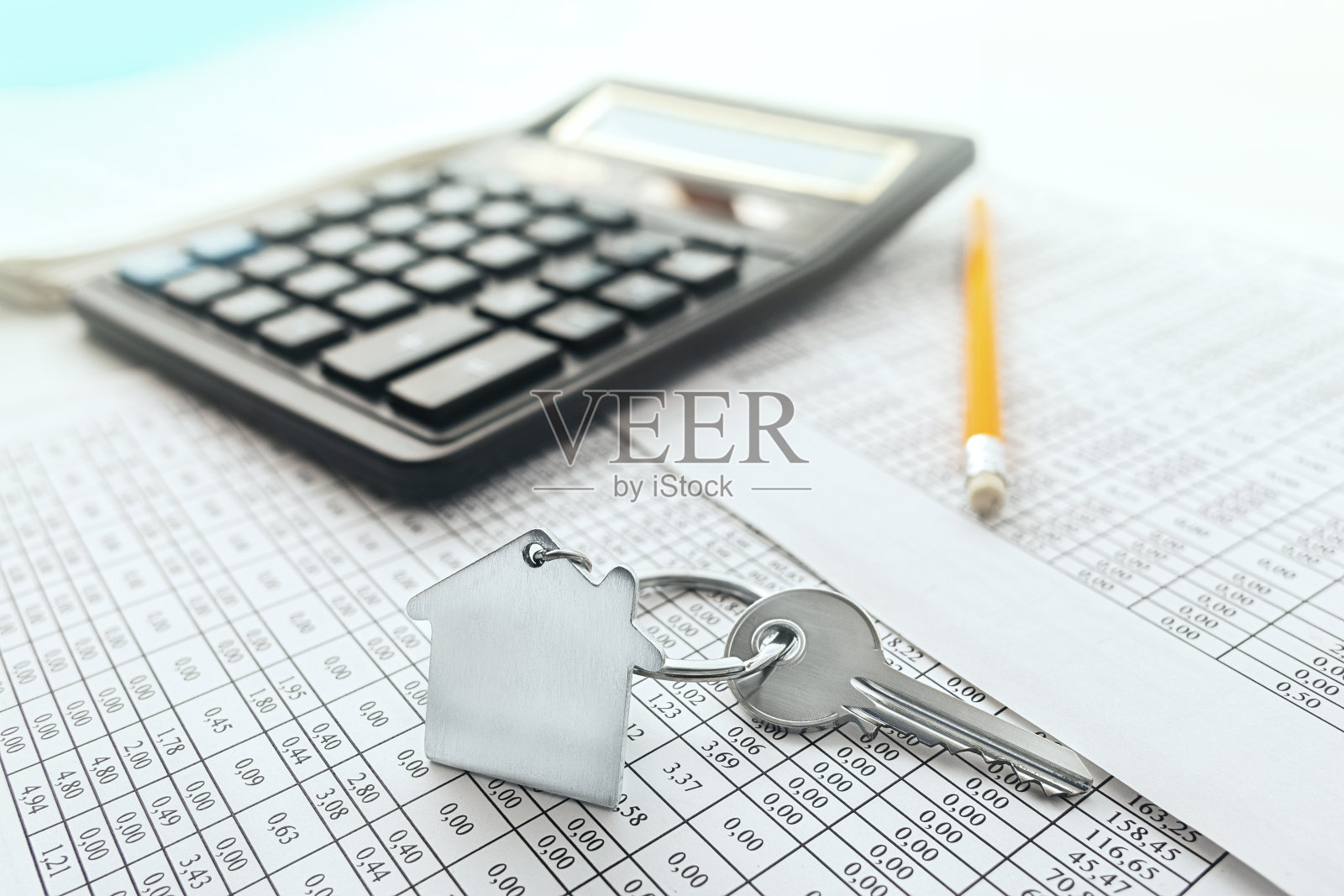 房产,带房子标志的钥匙链。计算器与财务空白。照片摄影图片