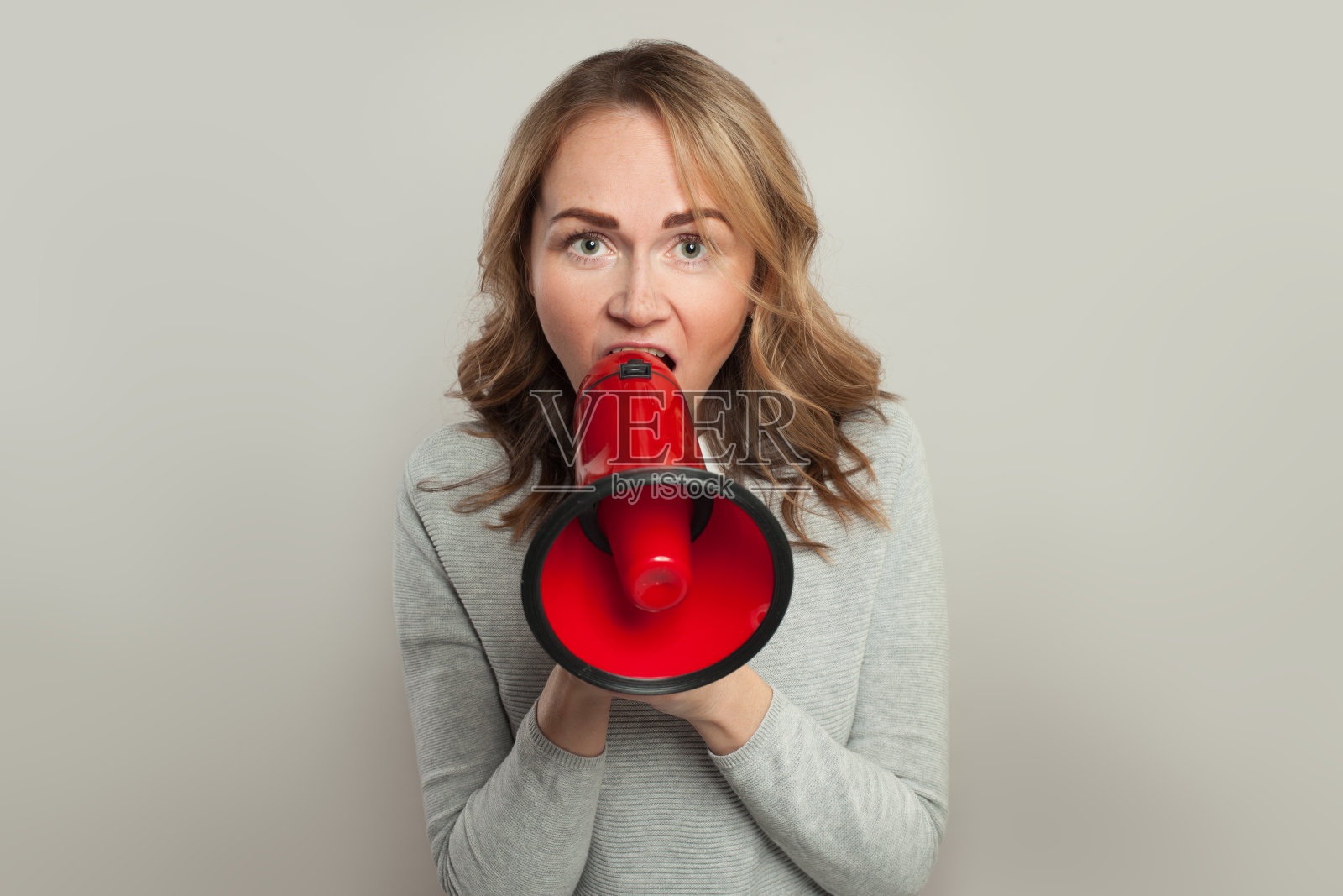女人用红色的扩音器尖叫。女孩拿着扩音器在白旗上照片摄影图片