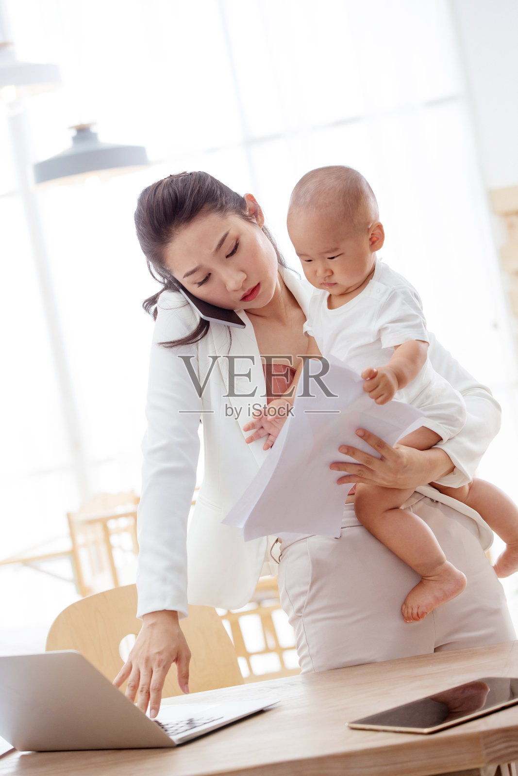 年轻的母亲在家带着孩子工作照片摄影图片