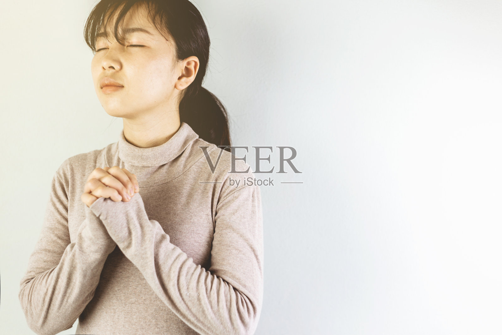 年轻的妇女戴着卫生面具在早上祈祷。照片摄影图片