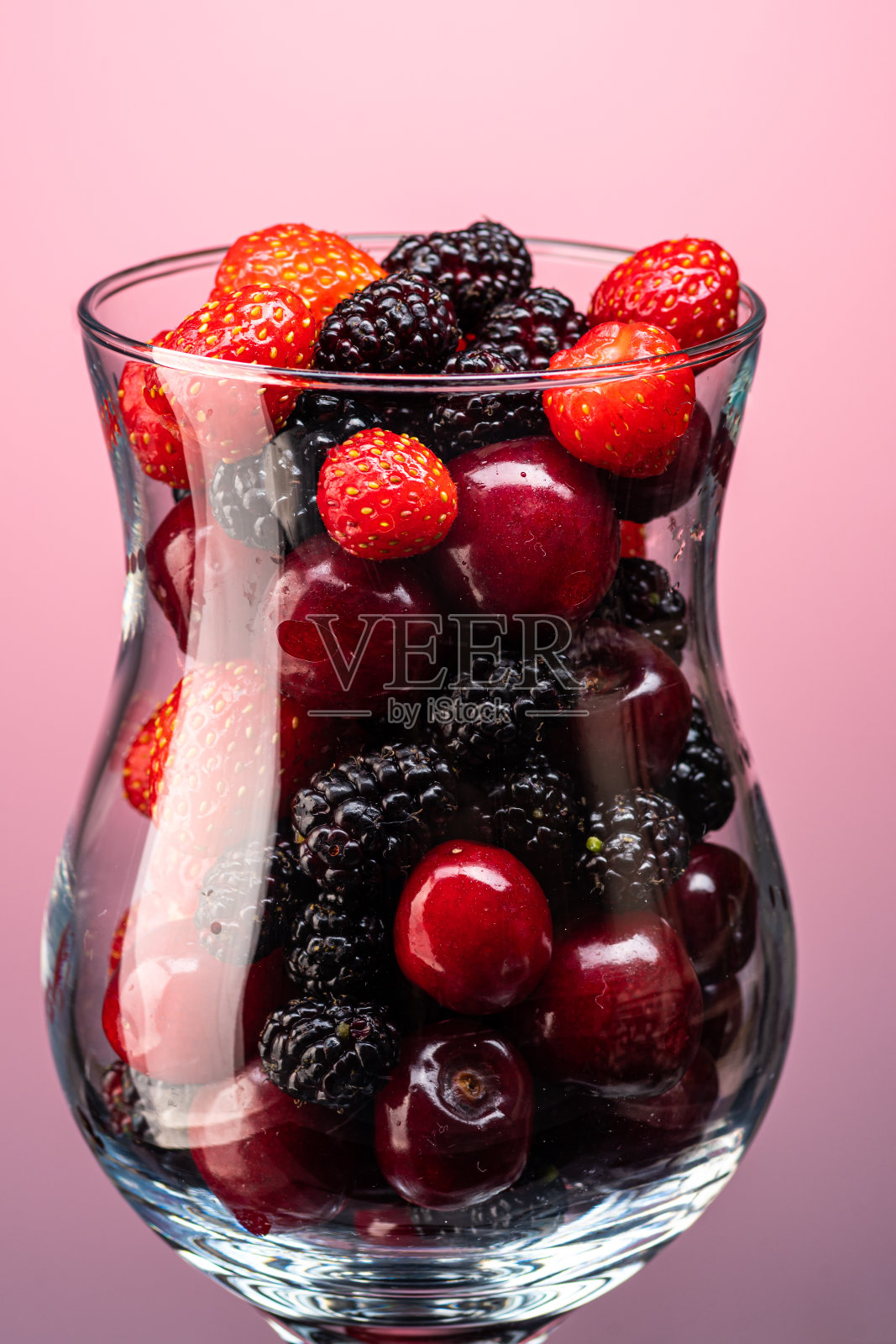 混合樱桃,草莓和桑葚在一个透明的玻璃梯度背景照片摄影图片